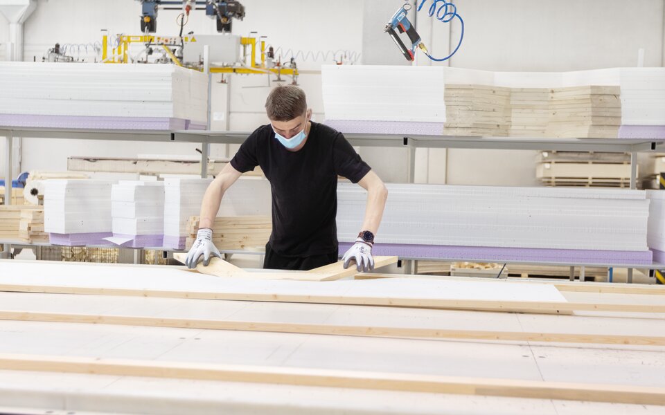 Mitarbeiter in Produktion mit Mundschutz bei der Arbeit mit Holzteilen