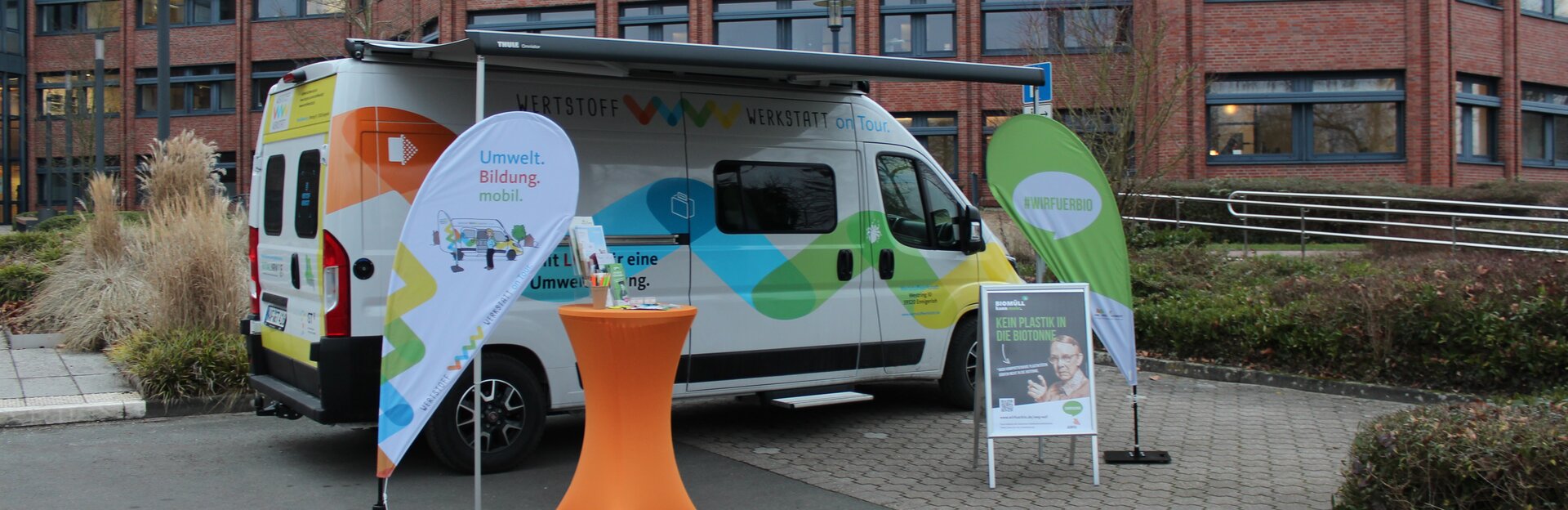 Wertstoff Werkstatt Informationsstand mit Wohnmobil, einem Tisch und Aufstellplakaten