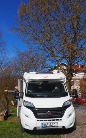 Mann winkt aus stehendem LMC Wohnmobil
