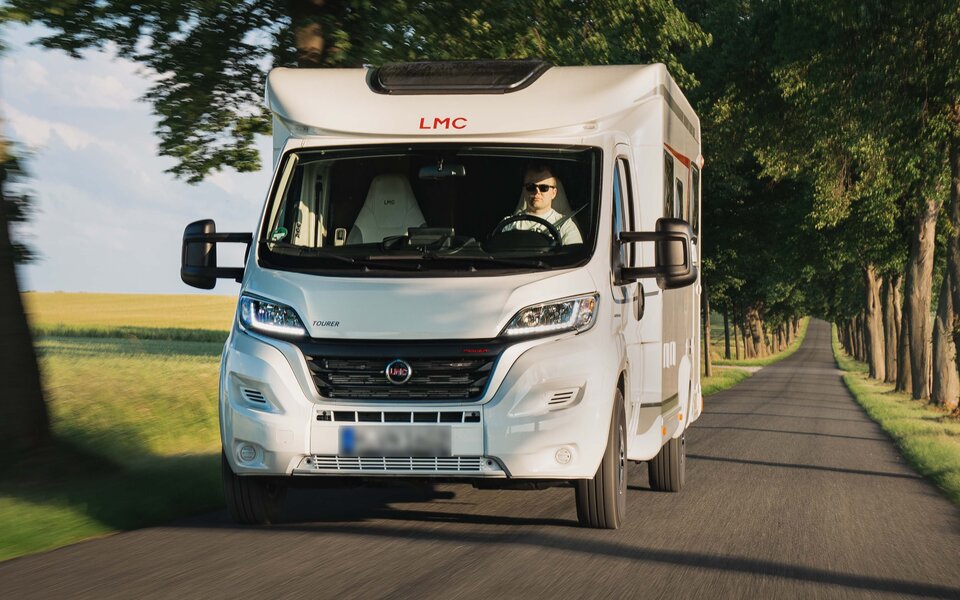lmc-tourer-Mann-fährt-Wohnmobil-auf-einer-Straße