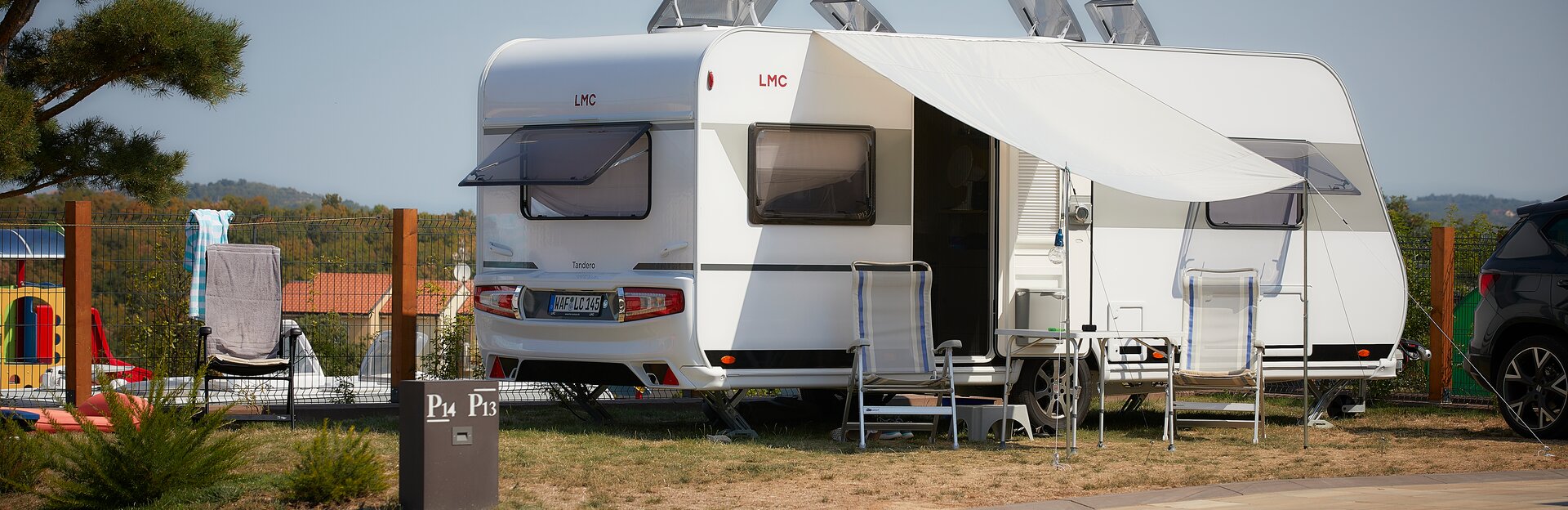 Offener LMC Wohnwagen auf Campingplatz mit Campingstühlen