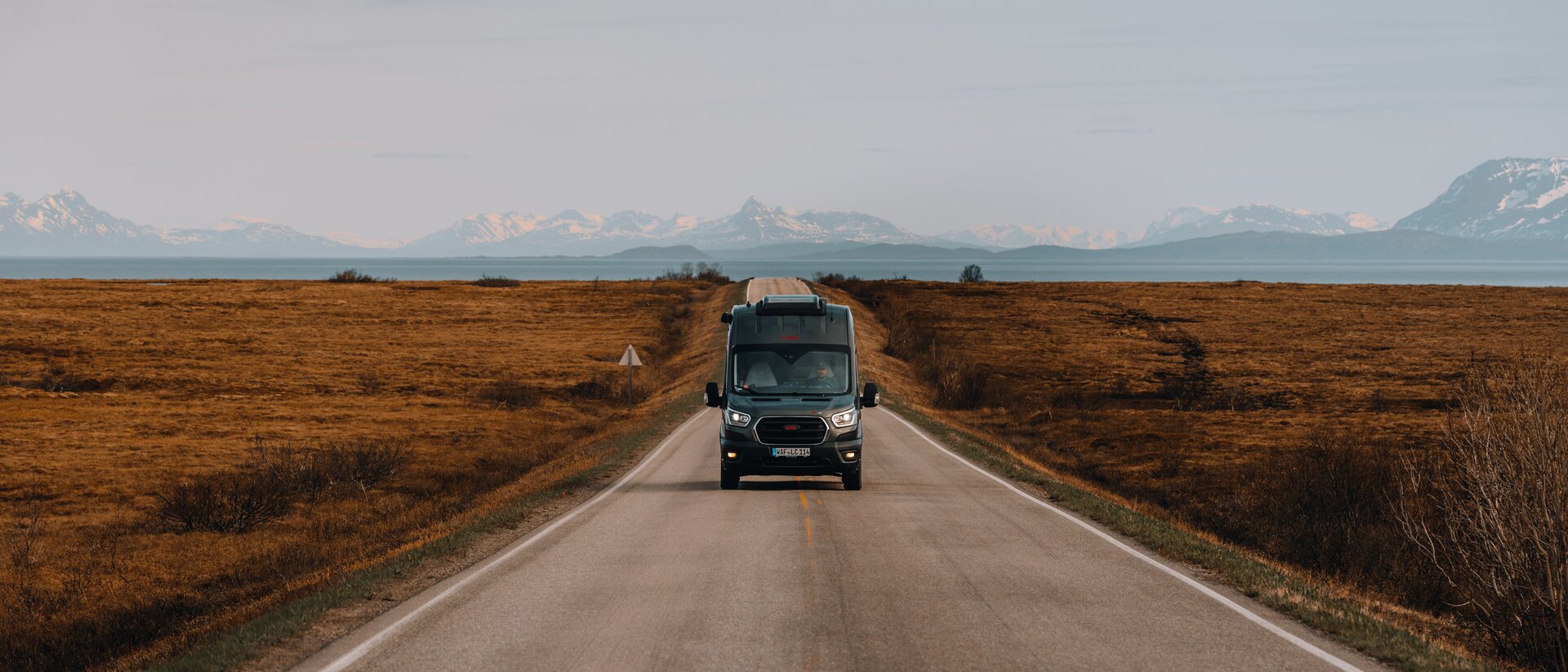 Campervan auf Landstrasse Berge im Hintergrund