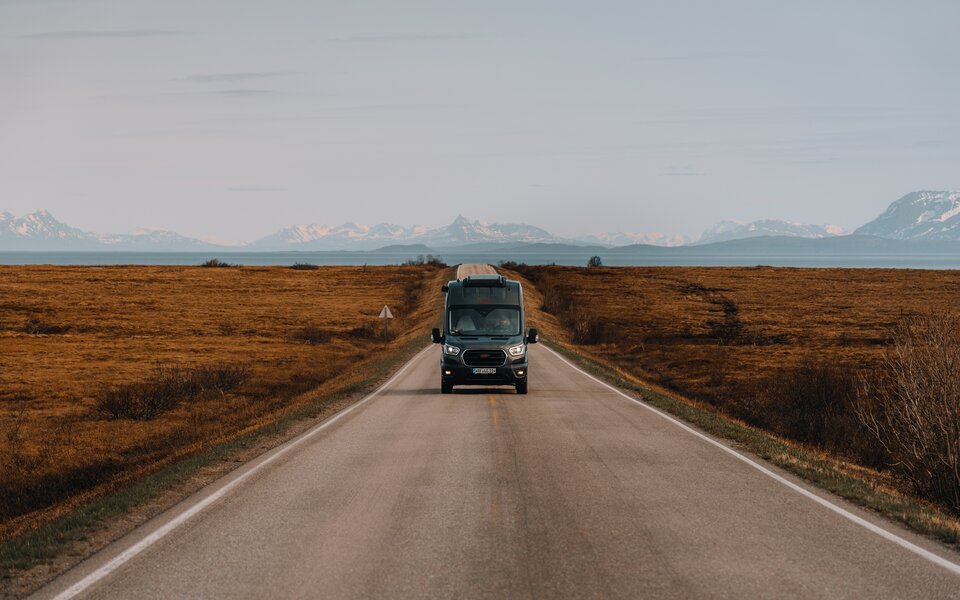 Campervan auf Landstrasse Berge im Hintergrund