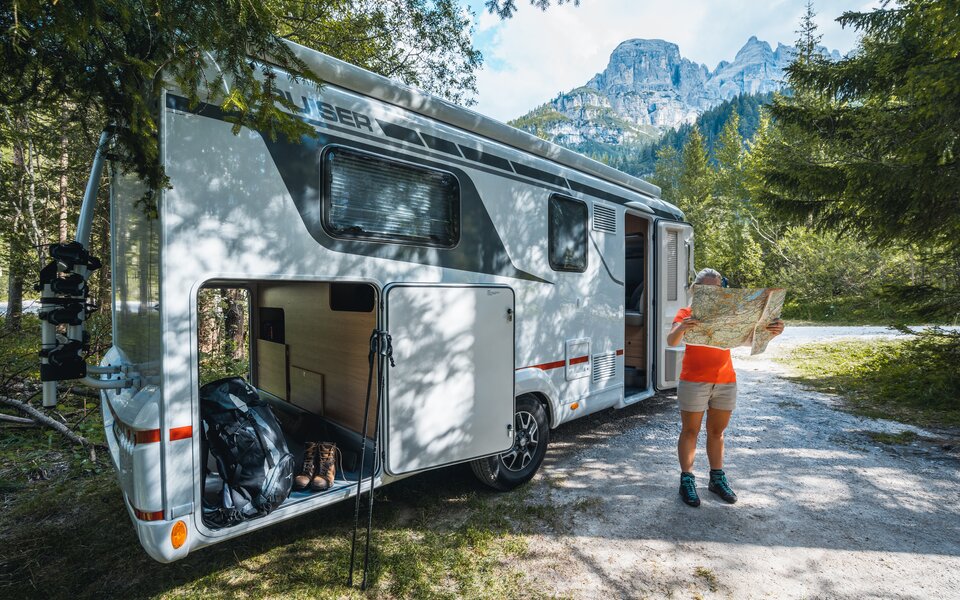 Frau mit Landkarte und Wanderkleidung vor Wohnmobil