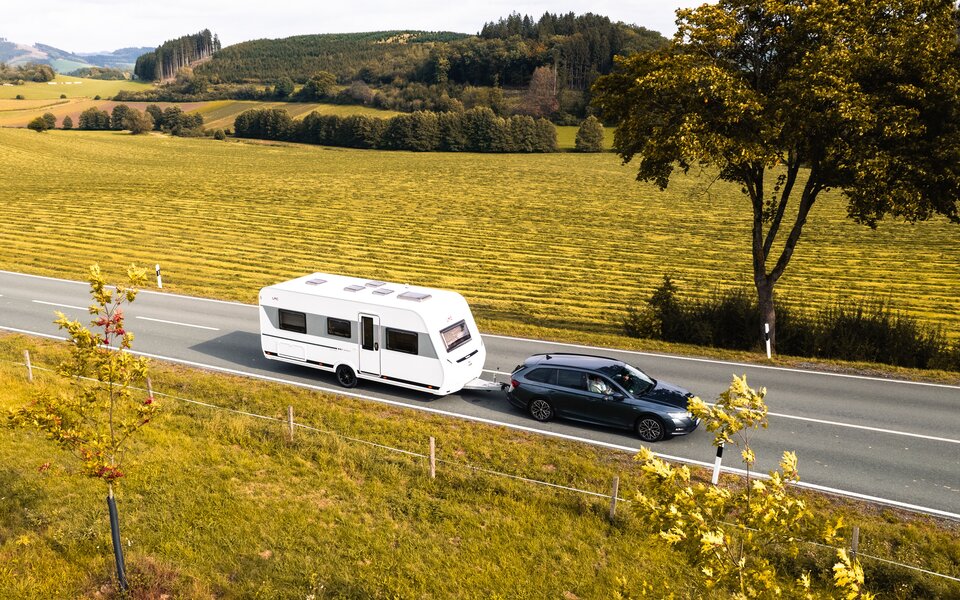Wohnwagen mit Auto auf Feldweg