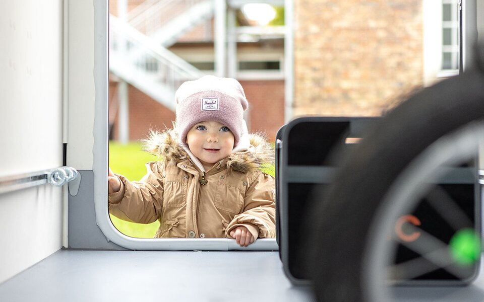 Kind schaut durch Fenster in Campingfahrzeug 