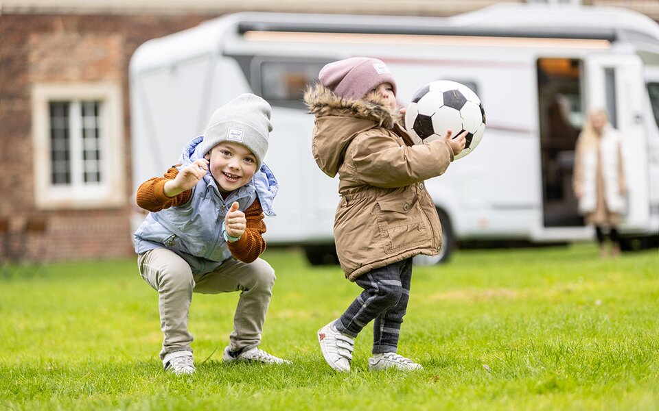 Kinder spielen Ball vor Wohnmobil