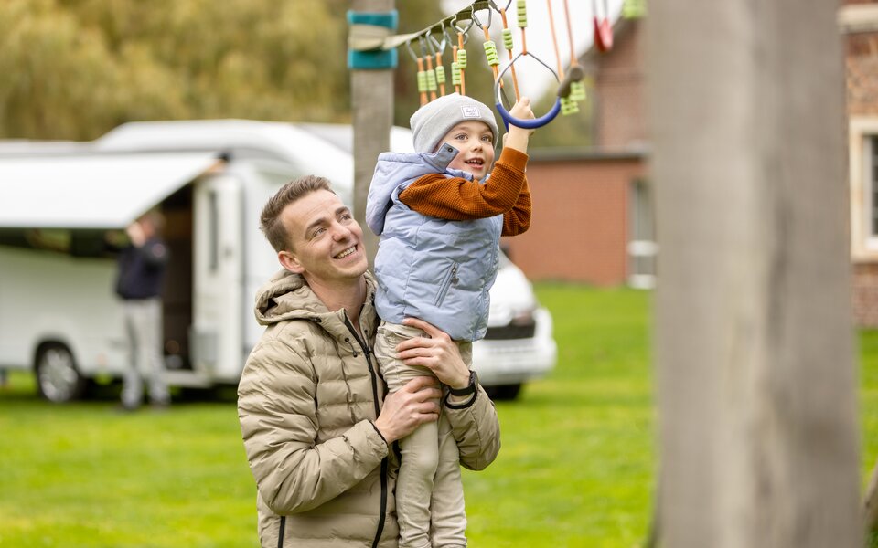 Kind hangelt an Spielplatz mit Vater 