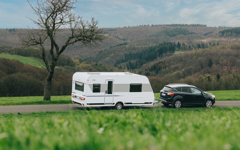 Wohnwagen LMC Tandero unterwegs im Frühling auf der Straße. 