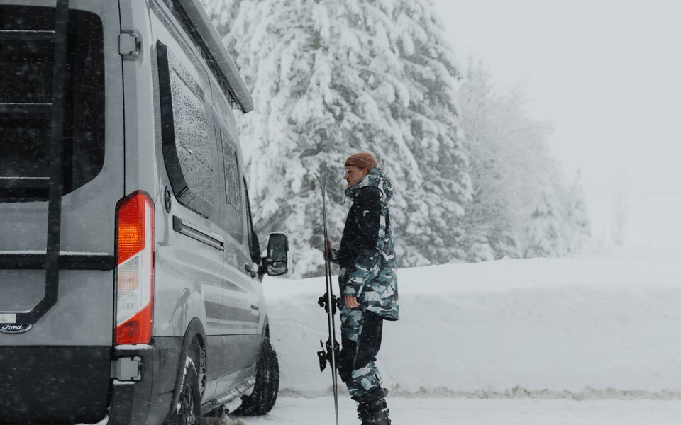 Snowboardfahrer in Winterlandschaft mit LMC Camper Van Innovan active