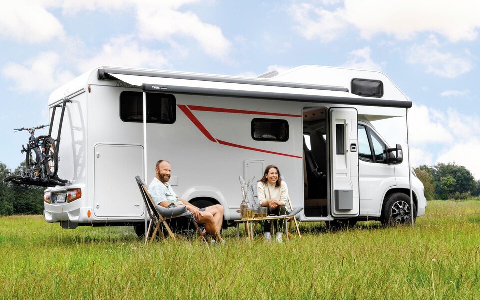 Pärchen sitzt vor dem LMC Wohnmobil Tourer Alkoven