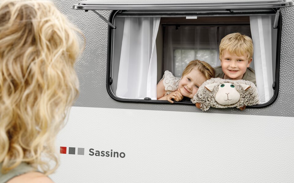 2 Kinder schauen aus einem geöffneten LMC Sassino Fenster raus